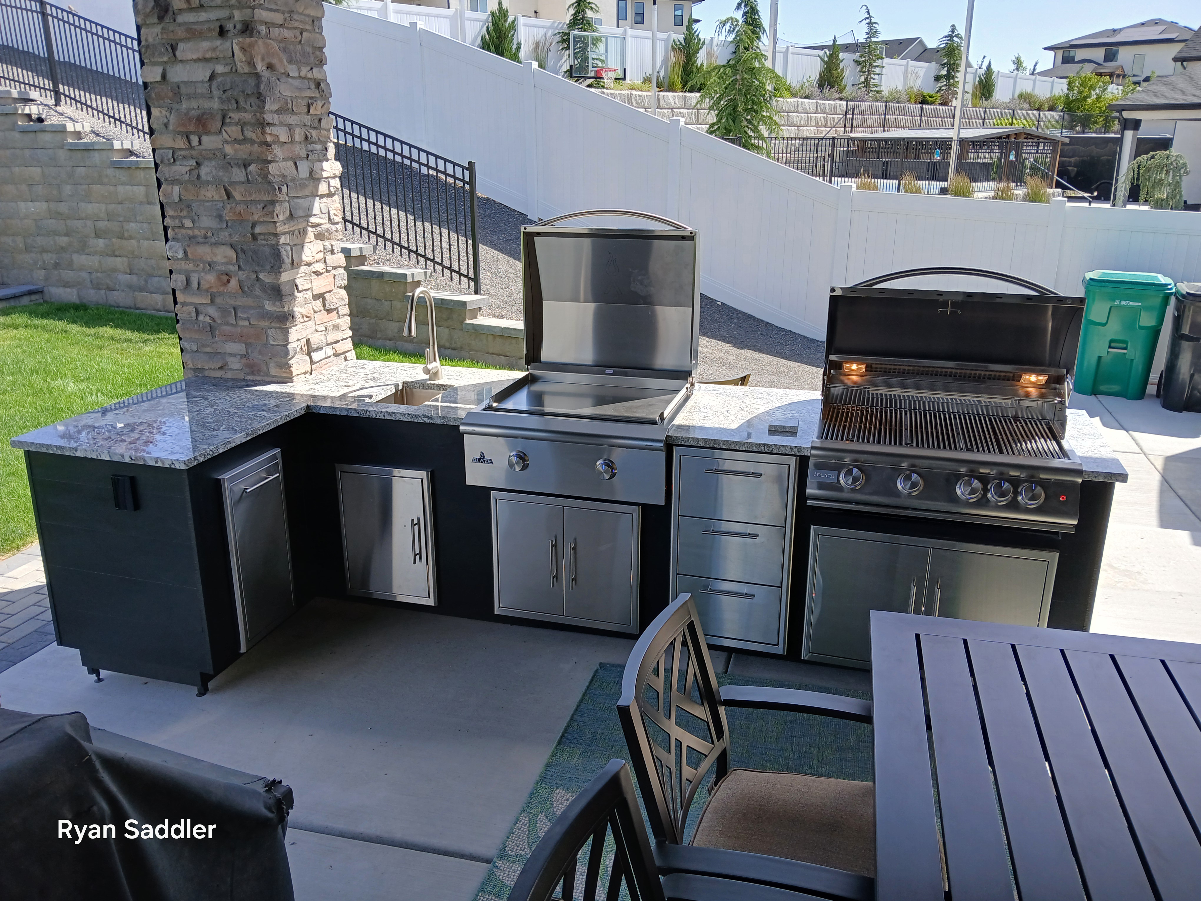 L-shaped outdoor kitchen with steel siding and granite countertop